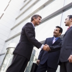Group of businessmen shaking hands outside office