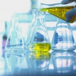 yellow solution in glass flask with scientist hand in science la