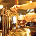 gold beer in the hand and beer taps