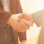 Business handshake with sun rays