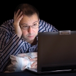 man with computer in bed