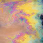 Petrol stain on asphalt road, big polluted puddle water.