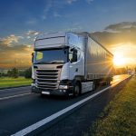White trucks arriving on the asphalt road in rural landscape in
