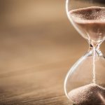 Sand running through the bulbs of an hourglass measuring the pas