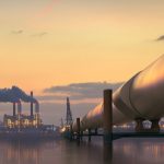 Oil pipeline in industrial district with factories at dusk