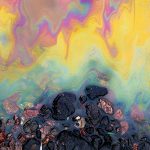 Petrol stain on asphalt road, big polluted puddle water.