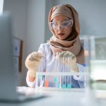 Young chemist wearing gloves working with test tubes